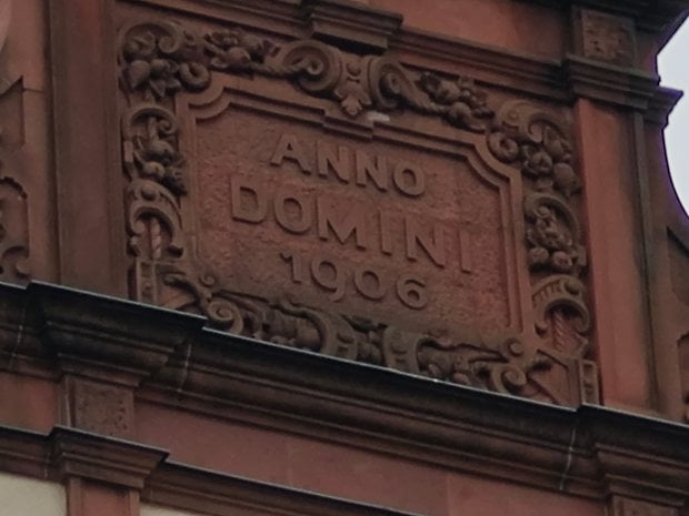 Inscription sur un bâtiment : ANNO DOMINI 1906, ornée de sculptures élaborées.