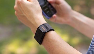 A close-up of a wrist with an Amazfit Helio strap, holding a smartphone.