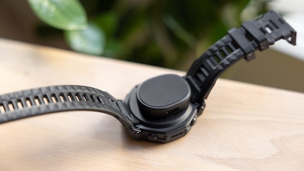 Amazfit T-Rex Pro 3 smartwatch on a wooden surface, showcasing its rugged design and flexible strap.