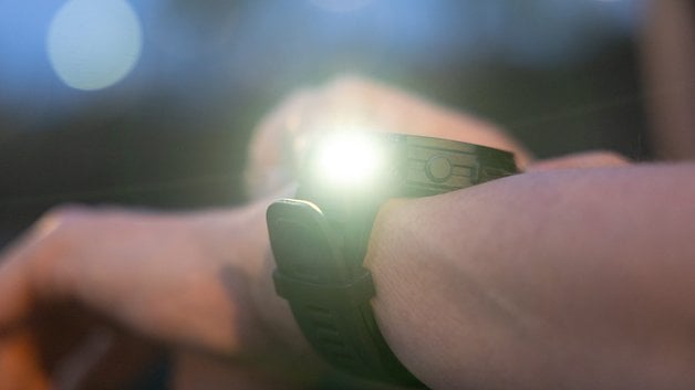 A close-up of an Amazfit T-Rex Pro 3 smartwatch with a glowing display on a wrist.