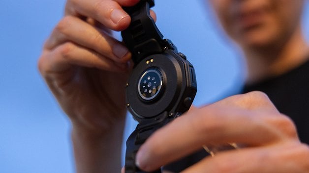 A person holding the Amazfit T-Rex Pro 3 smartwatch, showing its back features.
