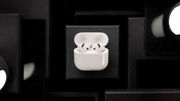 White Apple AirPods in their charging case on a dark background.