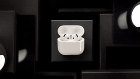 AirPods brancos da Apple em seu estojo de carregamento sobre um fundo escuro.