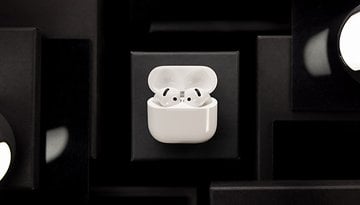 AirPods brancos da Apple em seu estojo de carregamento sobre um fundo escuro.