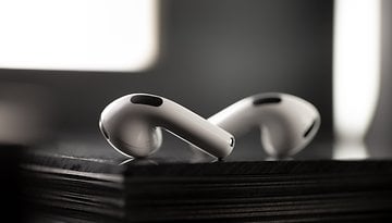 Nahaufnahme von Apple AirPods, die auf einer schwarzen Oberfläche liegen und ihr elegantes Design zeigen.