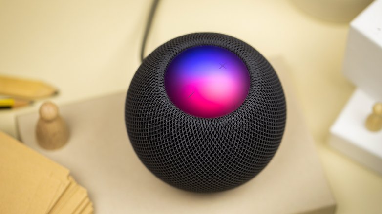 The HomePod mini on the table with colorful lights displaying on the top touch screen