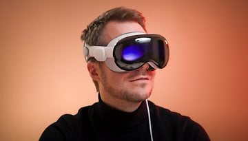 Une personne portant un casque de réalité augmentée Apple Vision Pro sur un fond chaleureux.