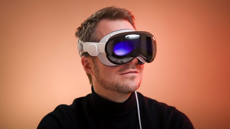 A person wearing Apple Vision Pro augmented reality headset against a warm background.