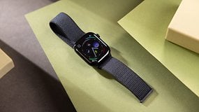 Eine schwarze Apple Watch Series 10 auf grünen und braunen Flächen, die verschiedene Apps anzeigt.