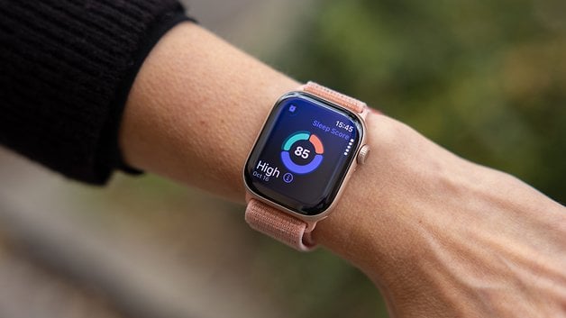 Eine Nahaufnahme einer Apple Watch, die eine Schlafbewertung von 85 am Handgelenk einer Person zeigt.