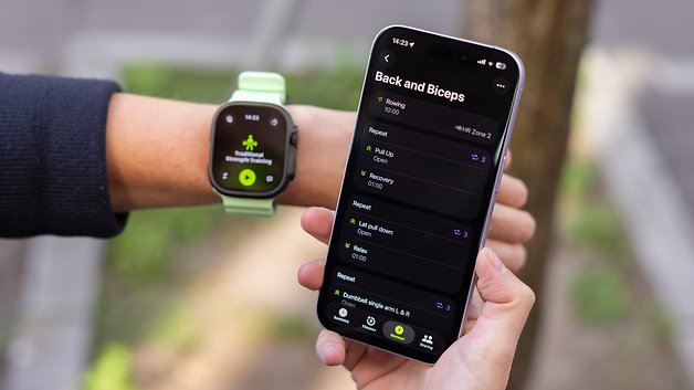 Eine Apple Watch zeigt Trainingsdetails am Handgelenk, neben einer Hand, die ein Smartphone mit Trainingsanweisungen hält.