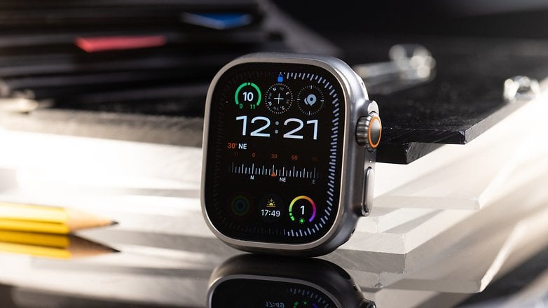 Apple Watch Ultra 2 affichant l'heure 12:21 et divers cadrans sur une surface réfléchissante.