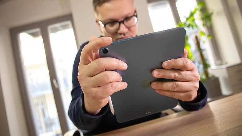 Fabi sitzt mit iPad Air in der Hand am Schreibtisch