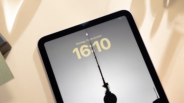 Apple iPad Mini 7 displaying the time 16:10 on a lock screen with a silhouette of a tower.