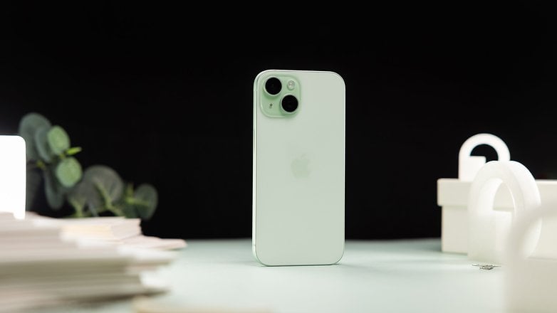 L'iPhone 15 vu de dos et posé verticalement sur une table avec un arrière-plan noir