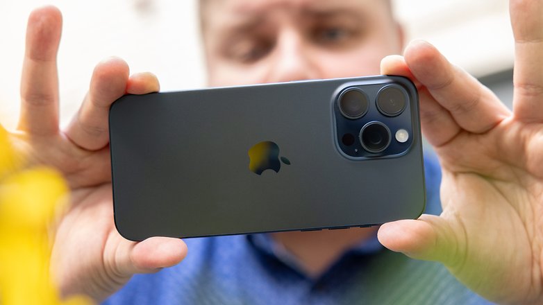 L'iPhone 15 Pro Max d'Apple tenu à deux mains horizontalement par Antoine et vu de dos