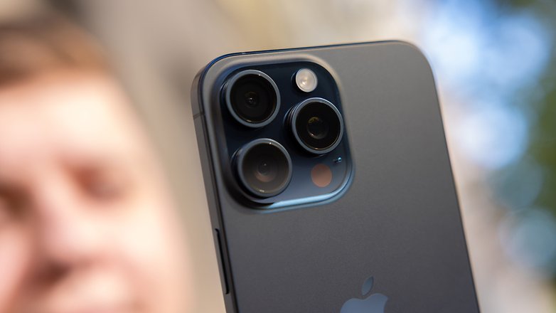 L'iPhone 15 Pro Max d'Apple vu de dos en plein soleil avec un zoom sur son module photo avec ses trois objectifs