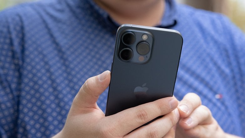 L'iPhone 15 Pro Max d'Apple tenu dans une main droite, vu de dos avec un zoom sur son module photo arrière