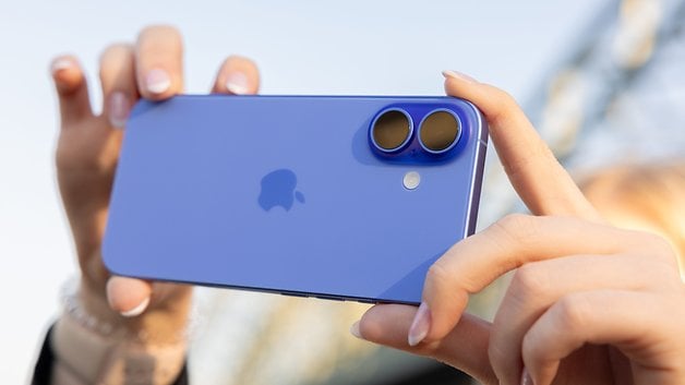 A person holding a blue iPhone 16 with dual cameras, focusing on the back of the device.