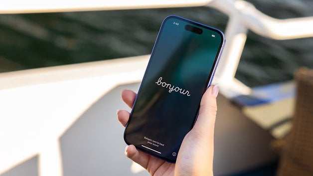 A person holding an iPhone 16 displaying the word 'bonjour' on the screen.