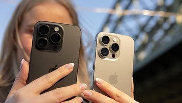 Deux iPhones tenus par une personne, l'un en noir et l'autre en argent, avec un arrière-plan flou.