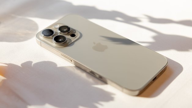 A close-up of tje iPhone 16 Pro lying on a light surface with soft shadows.