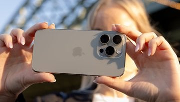 A person holding an iPhone 16 Pro facing the camera, showcasing its design and camera features.