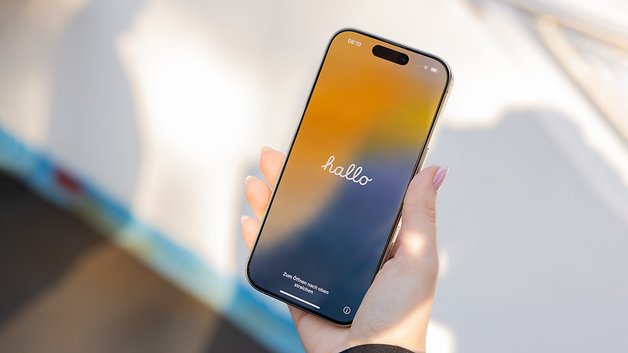 Segurando um iPhone 16 Pro que mostra uma tela colorida de "olá".