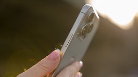 A person holding an iPhone 16 Pro, showcasing its camera and side buttons in sunlight.
