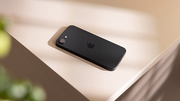 Um iPhone 16e preto da Apple colocado sobre uma superfície clara.