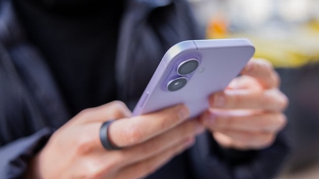 A person holding an Apple iPhone 17 in lavender color, using it with both hands.