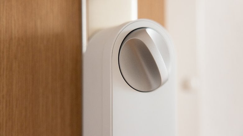 Close-up of an Aqara U200 Lite smart door lock knob on a wooden door.