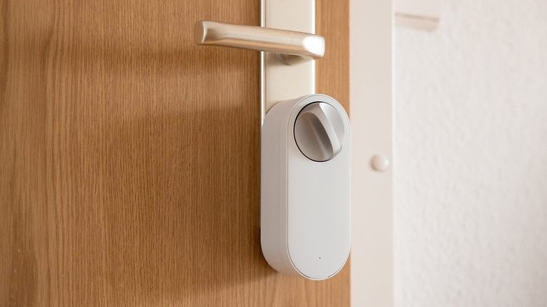 Smart door lock installed on a wooden door with a silver handle.
