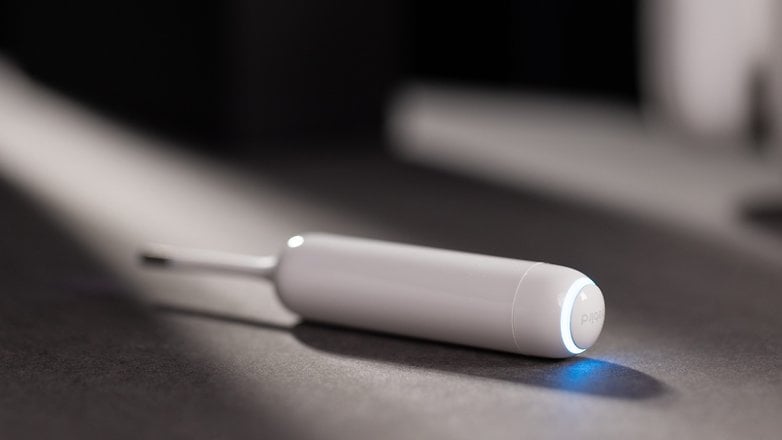 A sleek white tool with a glowing blue light, resting on a dark surface.