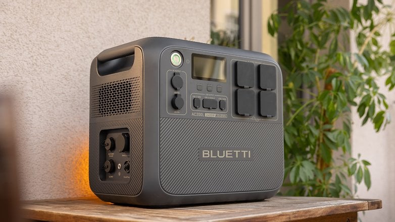 A Bluetti AC200L portable power station on a wooden table, with buttons and ports visible.