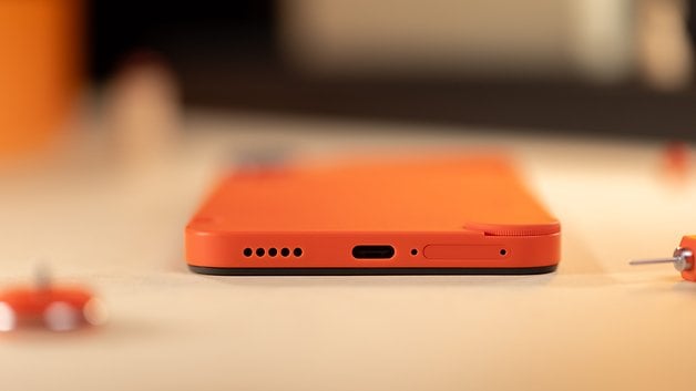 The CMF Phone 1 lies flat on a table, as seen from behind with a glimpse of its USB-C port.