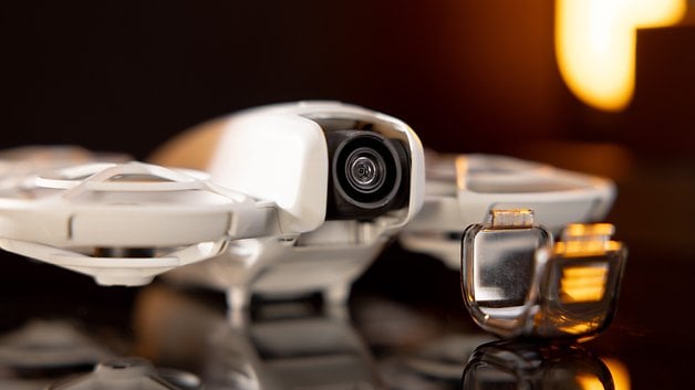 Close-up of the camera of a DJI Neo drone with protective covers next to it.