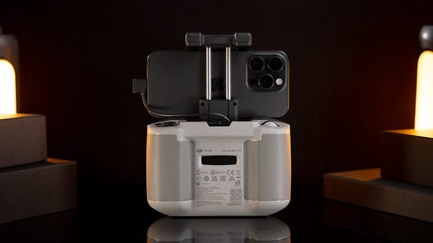 A DJI remote controller with an attached smartphone, against a dark background.