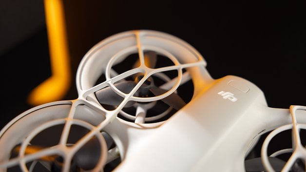 Close-up of a DJI Neo drone from above, showing its design and propellers against a dark background.