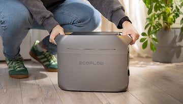 Eine Person, die sich hockt und das tragbare EcoFlow Delta 3 Plus Stromaggregat drinnen hält.