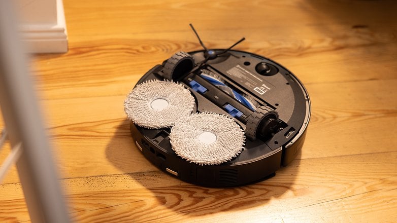 A robotic vacuum cleaner with mopping pads on a wooden floor.