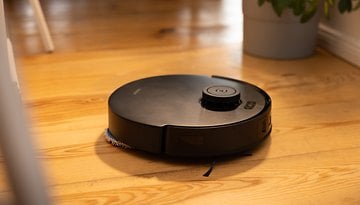 A black Ecovacs Deebot T30s Combo robot vacuum on wooden floor.