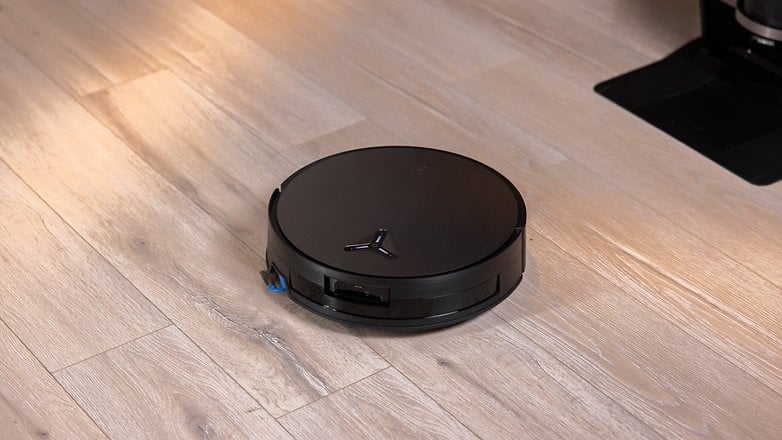 Ein schwarzer ECOVACS DEEBOT X11 OmniCyclone Saugroboter auf einem Holzboden. Ein schwarzer ECOVACS DEEBOT X11 OmniCyclone Saugroboter auf einem Holzboden.