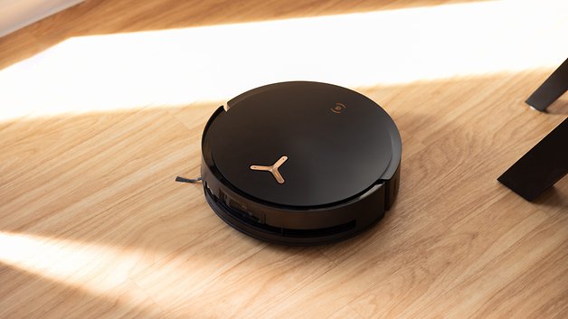 A black Ecovacs Deebot X8 Pro Omni robot vacuum cleaner on a wooden floor.