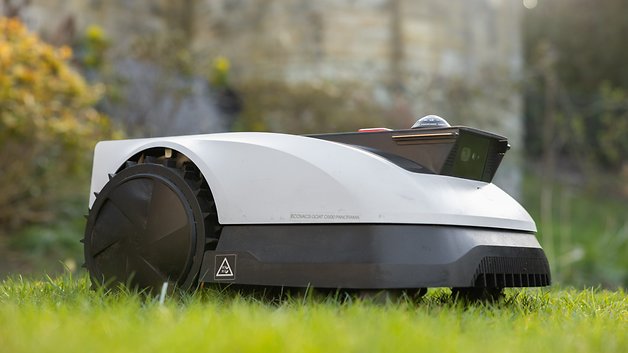 Une tondeuse à gazon robotisée Ecovacs GOAT O500 blanche sur l'herbe.