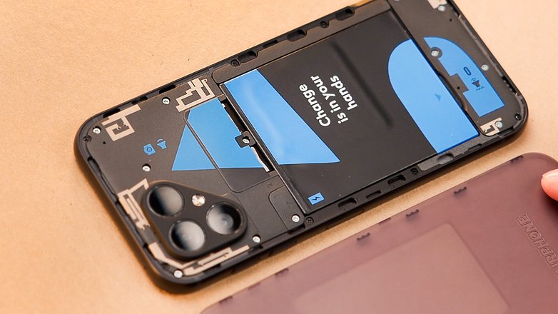 Le Fairphone 5 vu de haut sans son couvercle au dos et montrant la batterie qui bloque l'accès aux ports SIM et microSD