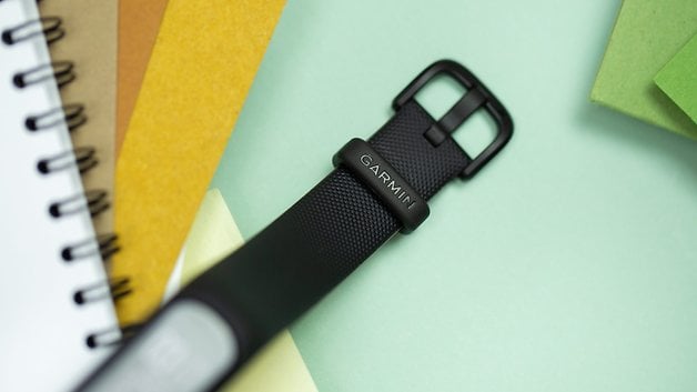 A close-up of a Garmin Vivosmart 5 fitness tracker on a pastel background with colored papers.