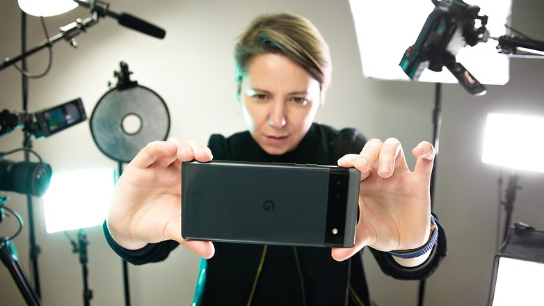 A person taking a picture with the Google Pixel 6a surround by lights
