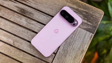 A Google Pixel 9 Pro smartphone in pink color resting on a wooden table.