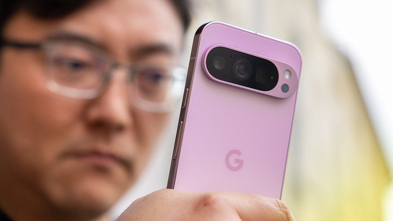 Une personne tenant un smartphone Google Pixel 9 Pro rose, en se concentrant sur le module de la caméra.